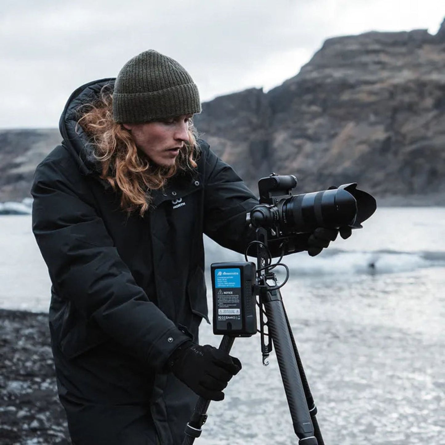 Tripod with mounted telephoto camera and accessory bag, black carbon-fiber legs