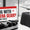 Wheeled black hard case with extended handle beside a boarding pass style label reading Flying With Camera Gear Read This First