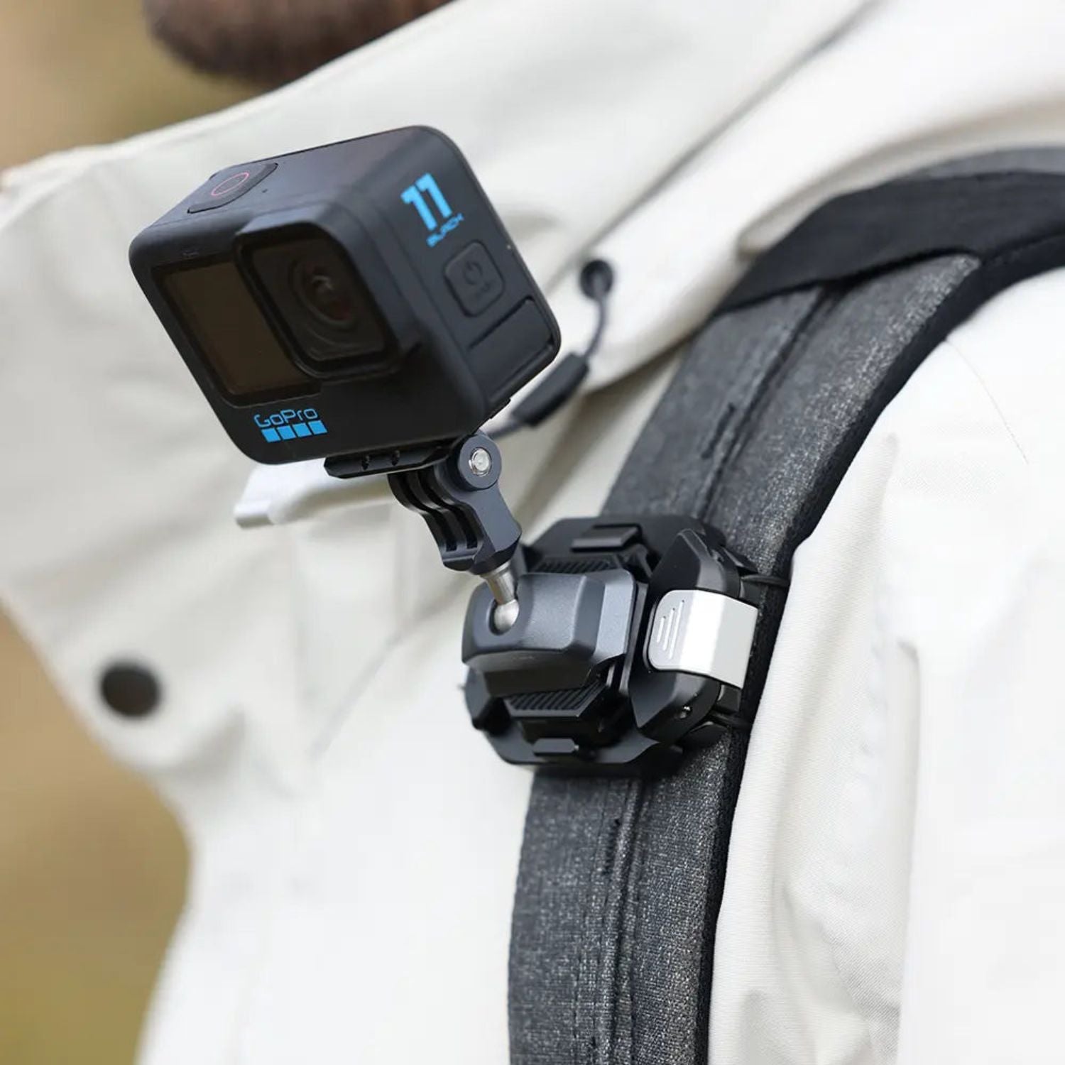 F38 quick release camera strap clip on gray backpack strap, holding a camera