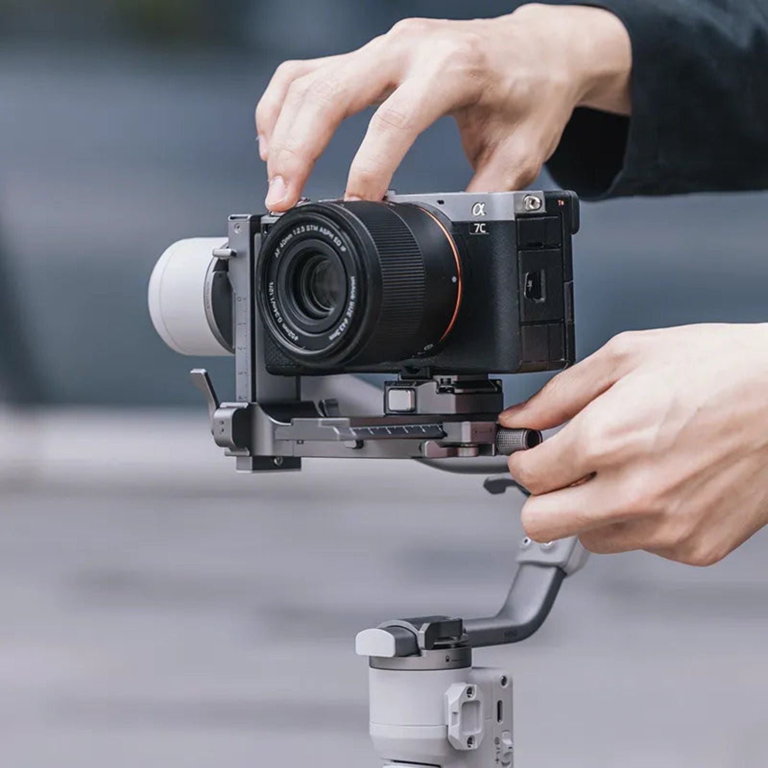 Camera on gimbal with quick-release clamp and rail, held during setup, dark gray