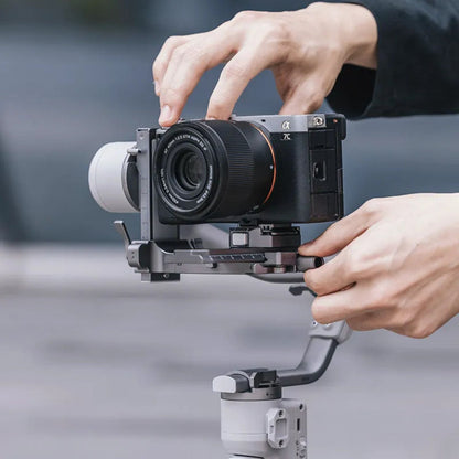 Camera on gimbal with quick-release clamp and rail, held during setup, dark gray