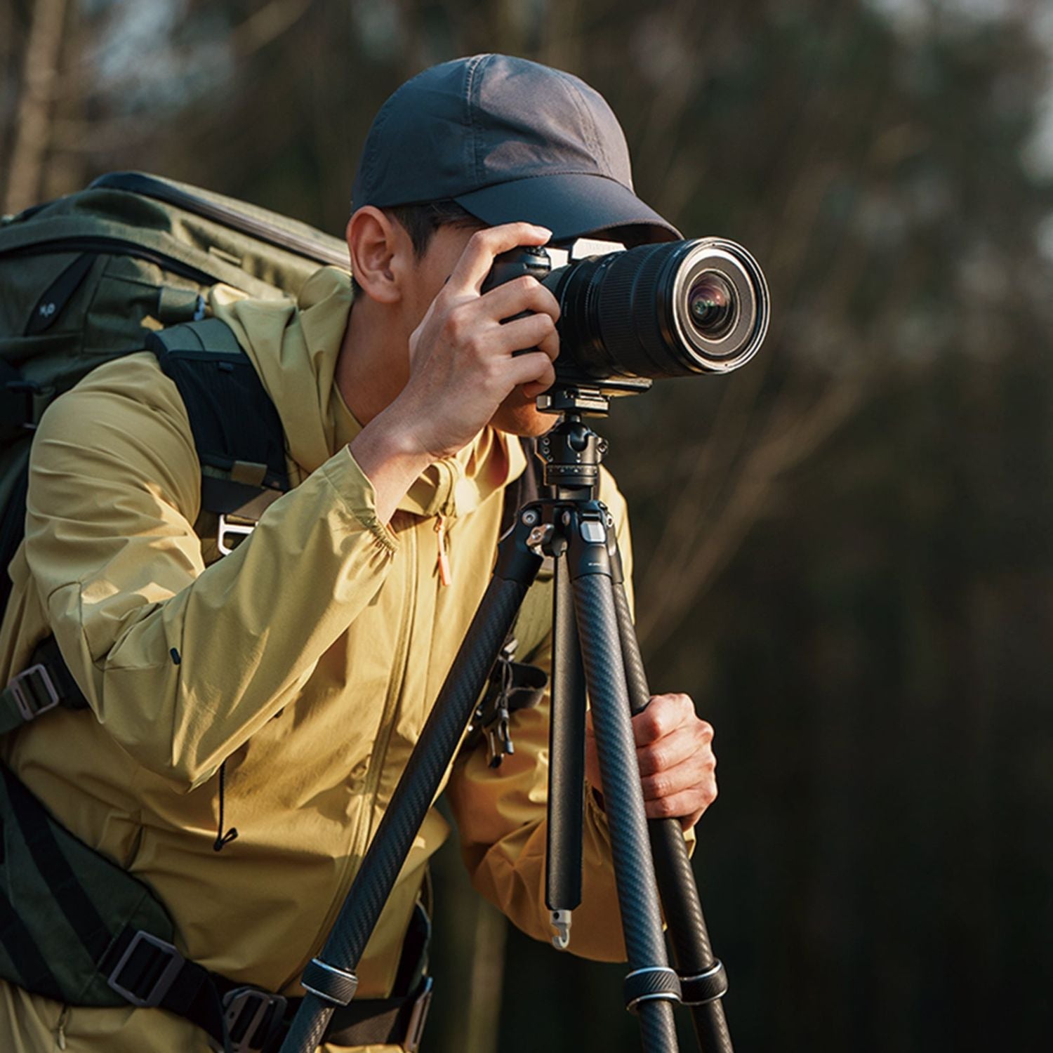 Tripod in use outdoors with photographer adjusting the camera mount