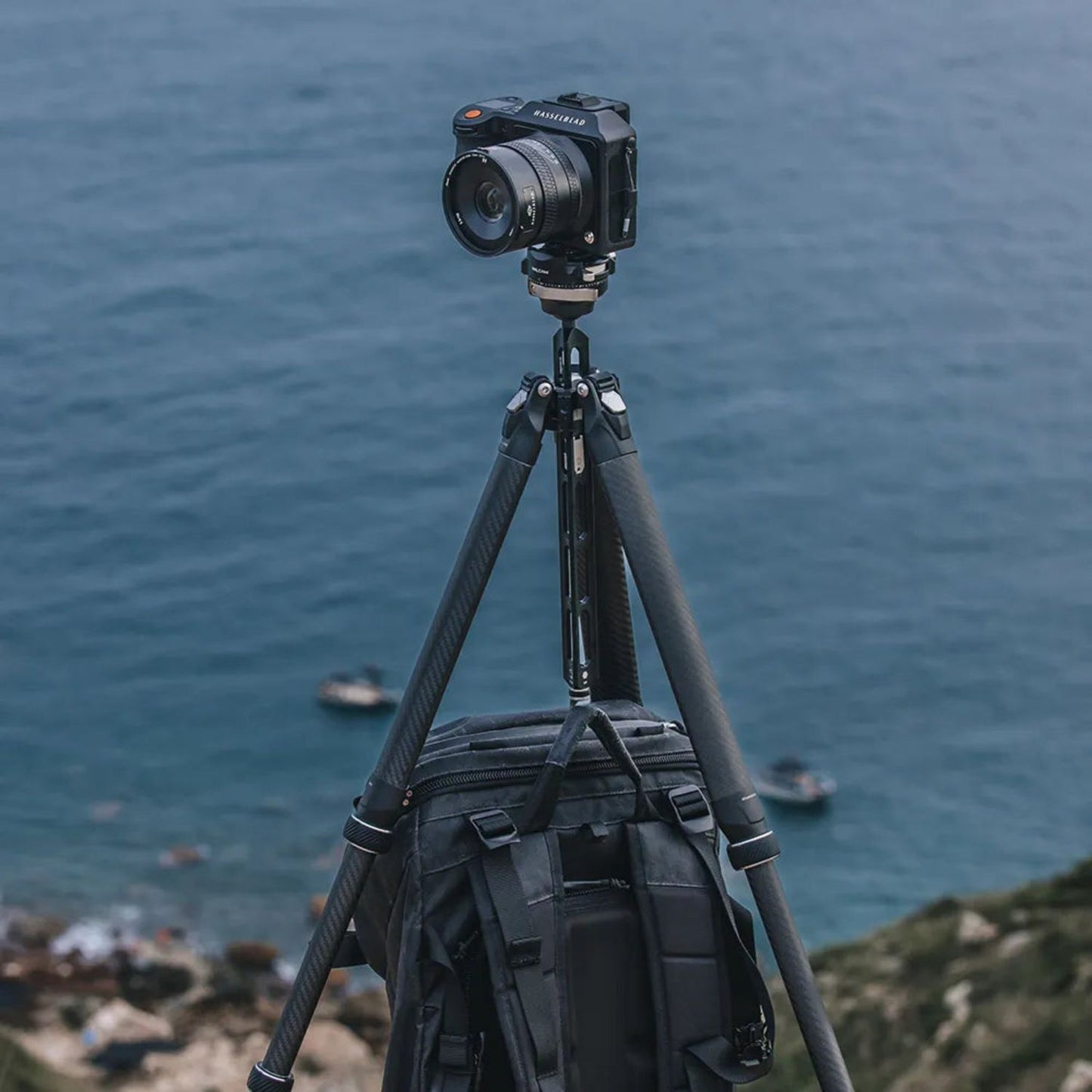 Tripod with mounted camera and black gear bag attached to the center legs
