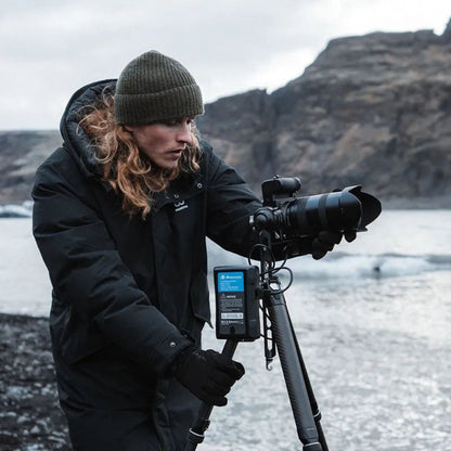 Tripod with mounted telephoto camera and accessory bag, black carbon-fiber legs
