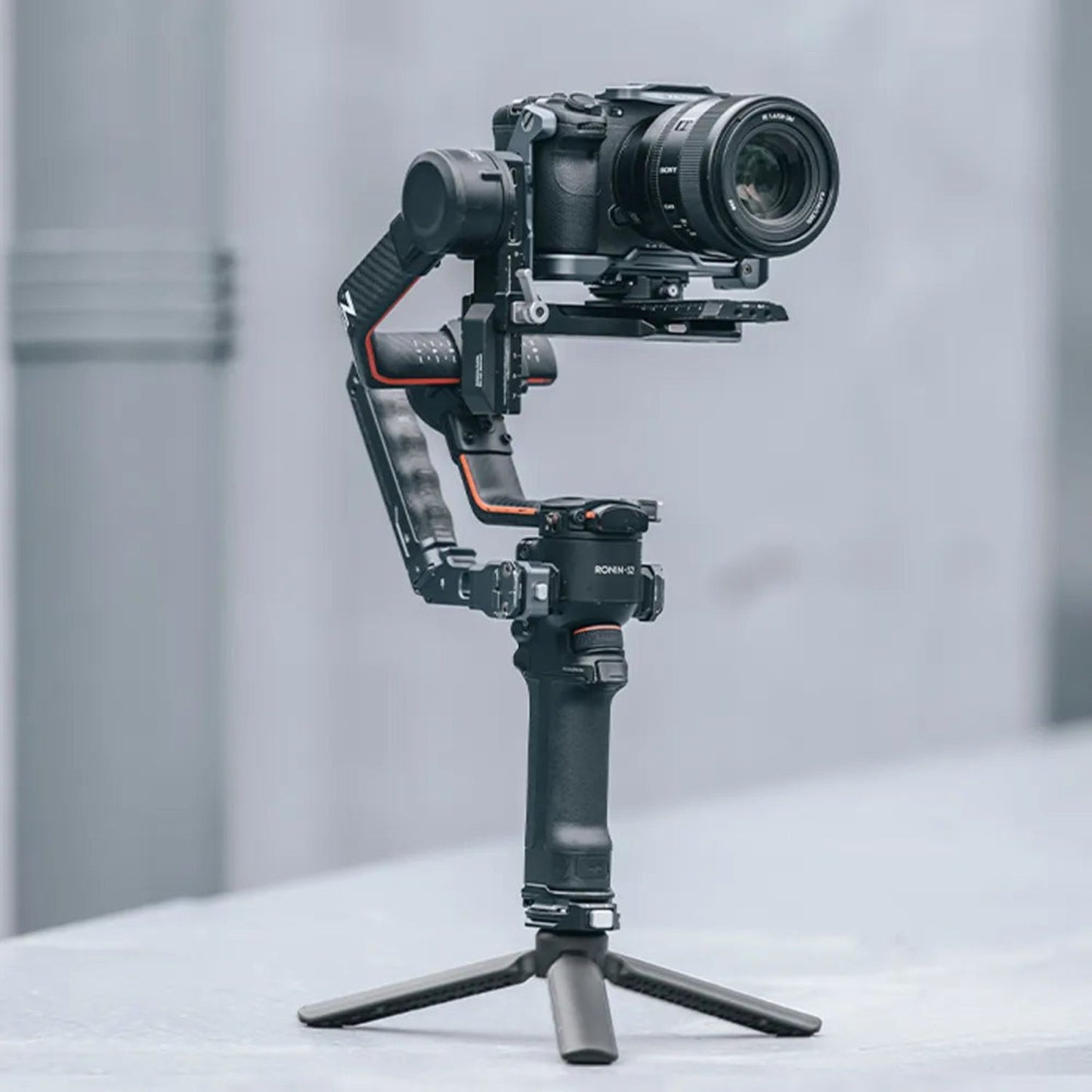 Black desktop tripod holding a camera on its head with three-point stand