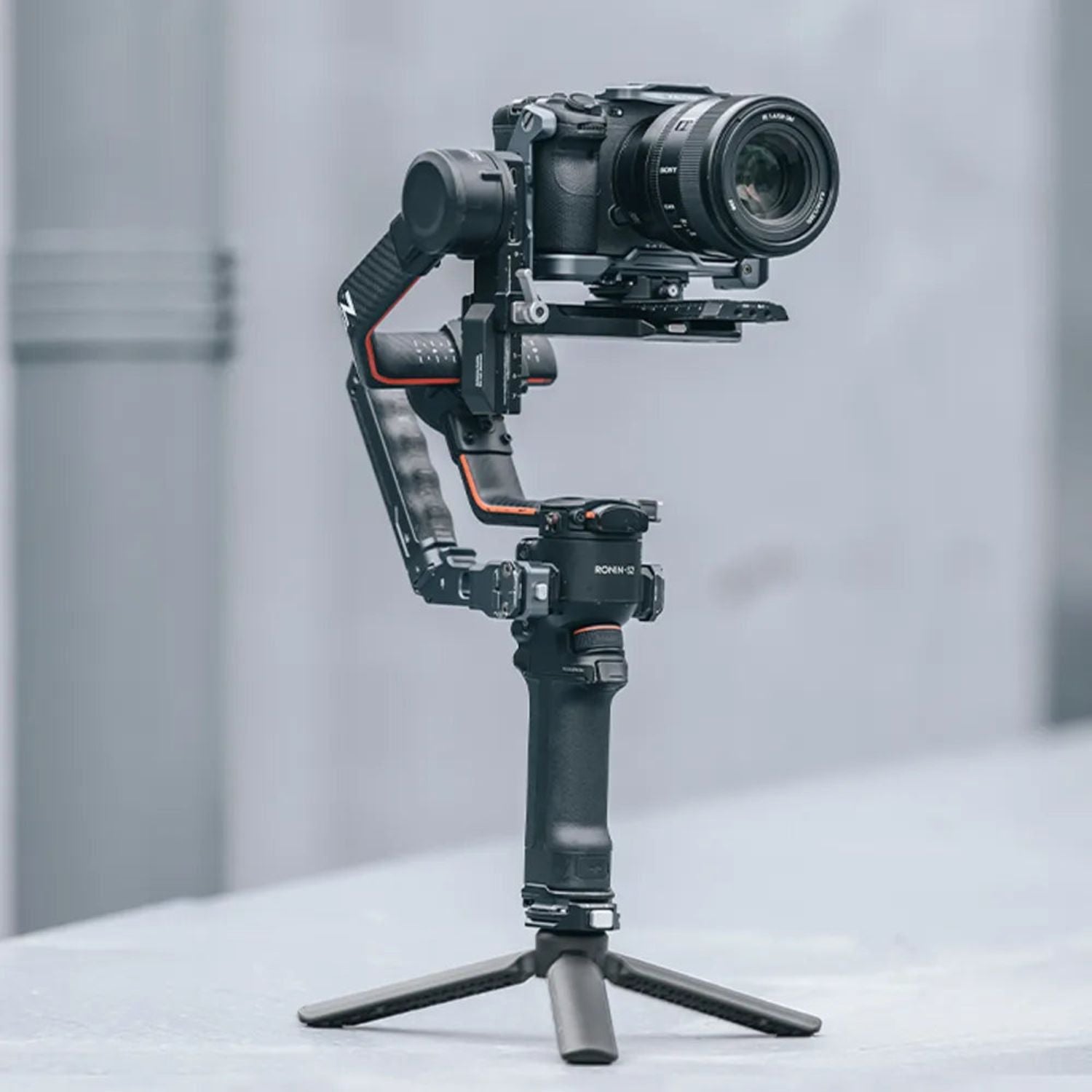 Black desktop tripod holding a camera on its head with three-point stand