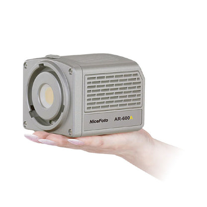 Portable LED video light in light gray housing, held in one hand